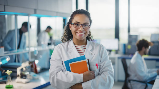 Student in a lab coat smiling in a modern research facility